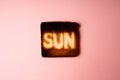 dark burnt slices of white bread toast with the word Sun on it on pink background.