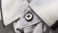 Dark button on a light textile shirt. Background of white shirt with stripes Royalty Free Stock Photo