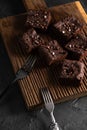 Dark cacao brownies with choco drops on ribbed oak wood cutboard on dark background