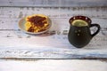 Dark ceramic tea mug with lemon and a plate with several fresh Viennese waffles with strawberry jam