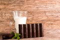 Dark chocolate bar, glass of milk and mint leaves on a wooden table Royalty Free Stock Photo