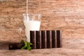 Dark chocolate bar, glass of milk and mint leaves on a wooden table Royalty Free Stock Photo