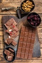 Dark chocolate bar with hazelnuts, peanuts, cranberries and freeze dried raspberries on a wooden board. wooden Royalty Free Stock Photo