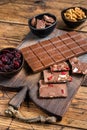 Dark chocolate bar with hazelnuts, peanuts, cranberries and freeze dried raspberries on a wooden board. wooden Royalty Free Stock Photo