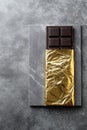 Dark chocolate bar on marble surface with gold foil wrapper Royalty Free Stock Photo