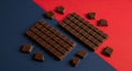 Dark Chocolate Bars Broken into Pieces on Red and Blue Background Royalty Free Stock Photo