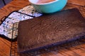 Dark chocolate cake cooling on rack on wooden table