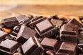 Dark chocolate cubes, coffee beans, peanuts and raisins on wooden table, close-up