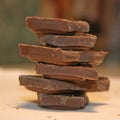 Dark chocolate. Multi-tiered tower. Close up. White background. Chocolate construction. Small pieces of a chocolate bar. Chunks a