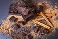 Dark chocolate stack, cinnamon and cocoa powder. Broken chocolate pieces and cocoa powder on black background. Dark chocolate bar. Royalty Free Stock Photo