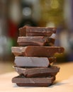 Dark chocolate. Stacked tower, stack. Seen close. White background. Chocolate construction. Small pieces of chocolate bar. Pieces