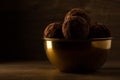 Dark chocolate truffles in golden bowl on wooden background, beautiful golden light Royalty Free Stock Photo