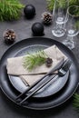 Dark christmas table setting design. Black plates, champagne glasses, fork and knife set with napkin, fir branch Royalty Free Stock Photo