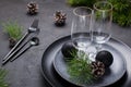 Dark christmas table setting design. Black plates, champagne glasses, fork and knife set with napkin, fir branch Royalty Free Stock Photo
