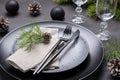 Dark christmas table setting design. Black plates, champagne glasses, fork and knife set with napkin, fir branch Royalty Free Stock Photo