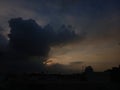 Dark clouds dominate the sky, partially obscuring the setting sun, resulting in a dramatic contrast of light and shadow Royalty Free Stock Photo