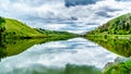 Dark Clouds and surrounding Mountains reflecting on the smooth water surface of Trapp Lake