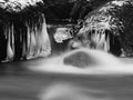 Dark cold water of mountain stream in winter time, small icicles. Royalty Free Stock Photo