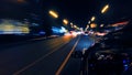 A dark-colored car is moving rapidly along the illuminated street Royalty Free Stock Photo