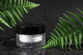 Dark cosmetic background. Jar of moisturizing face cream in a container, with water drops isolated on black background with