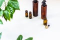 Dark cosmetic bottles and green natural leaves on a light background. Copy space Beauty salon blogger, salon therapy