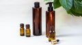 Dark cosmetic bottles and green natural leaves on a light background. Copy space Beauty salon blogger, salon therapy, minimalist