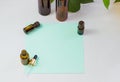 Dark cosmetic bottles and green natural leaves on a light background. Green empty card, sheet for writing. Layoutfor adding