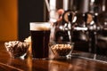 Dark craft beer with snacks. Near are pistachios, chips and nuts in plates and dark beer with foam