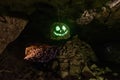 Dark creepy glowing phosphorescent smiling face on hanging stone in cave Royalty Free Stock Photo