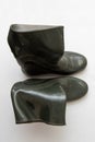Dark crumpled rubber boots stand, isolated forn, close-up
