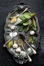 Dark culinary background with bay leaves, salt, pepper and garlic, view from above, copy space for recipe text