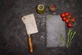 Dark culinary background with empty black slate board, meat hatchet, cherry tomatos, pepper and space for text