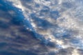 Dark Cumulus and light feathery clouds on the blue sky.