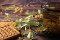 A dark cup of health tea, linden flowers and squares of cookies are on the table. Royalty Free Stock Photo