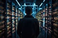 In Dark Data Center-Back View of IT Specialist Stands Beside the Row of Operational Server Racks. Concept for Cloud Computing,