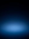 A dark, deep navy blue background with a bright, luminous, soft blue spotlight emanating from the bottom center, creating a Royalty Free Stock Photo