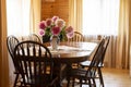 Dark dining table with wooden chairs and a vase with peonies flower in the living room