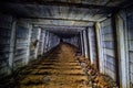 Dark dirty abandoned uranium mine with rusty remnants of railway