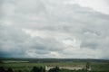 Dark dramatic rainy sky clouds over train composition in rural farm landscape