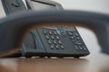 Dark earphone (receiver) with a corporate business landline telephone in the background