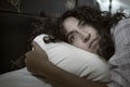 Dark and edgy portrait of depressed and sleepless latin woman lying worried and awake on bed at night suffering insomnia and Royalty Free Stock Photo