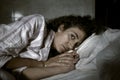Dark and edgy portrait of depressed and sleepless latin woman lying worried and awake on bed at night suffering insomnia and Royalty Free Stock Photo