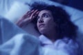 Dark and edgy portrait of depressed and sleepless latin woman lying worried and awake on bed at night suffering insomnia and Royalty Free Stock Photo