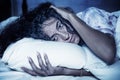 Dark and edgy portrait of depressed and sleepless latin woman lying worried and awake on bed at night suffering insomnia and