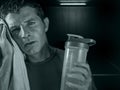 Dark edgy portrait of young sweaty tired and exhausted sport man with water bottle cooling off after hard fitness workout at gym Royalty Free Stock Photo