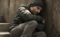 Dark and edgy urban portrait of middle aged sad and depressed unemployed man sitting outdoors on dirty street corner staircase Royalty Free Stock Photo