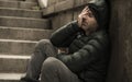 Dark and edgy urban portrait of middle aged sad and depressed unemployed man sitting outdoors on dirty street corner staircase Royalty Free Stock Photo