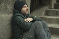 Dark and edgy urban portrait of middle aged sad and depressed unemployed man sitting outdoors on dirty street corner staircase Royalty Free Stock Photo