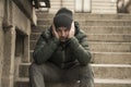 Dark and edgy urban portrait of middle aged sad and depressed unemployed man sitting outdoors on dirty street corner staircase