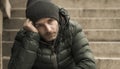 Dark and edgy urban portrait of middle aged sad and depressed unemployed man sitting outdoors on dirty street corner staircase Royalty Free Stock Photo